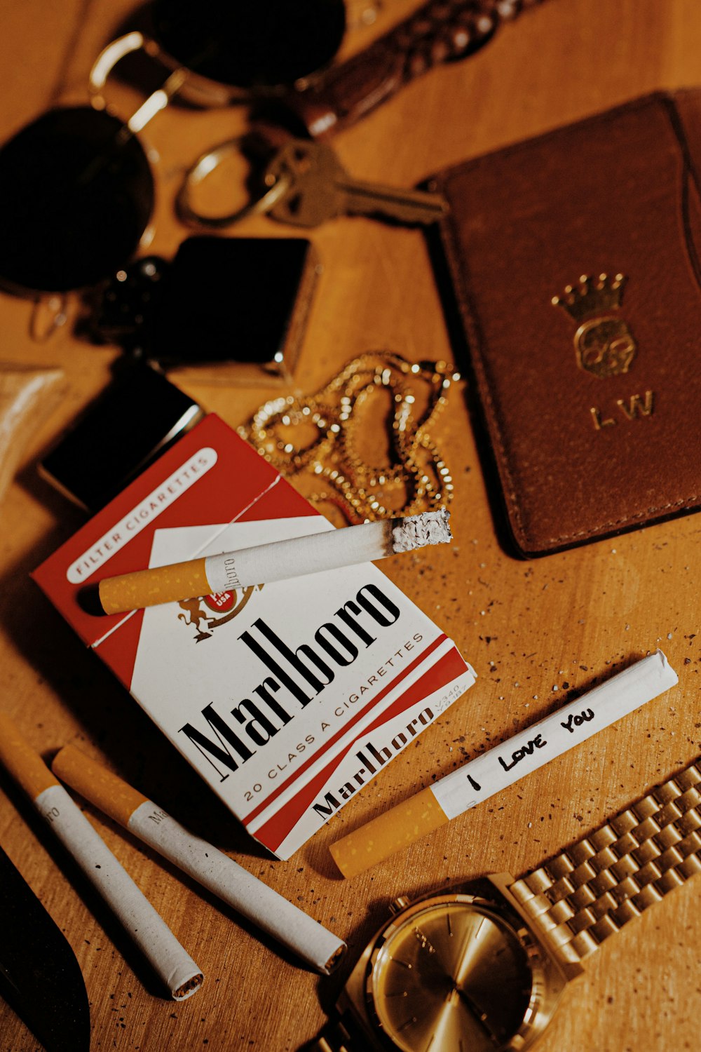 white and red marlboro cigarette pack beside brown leather bifold wallet