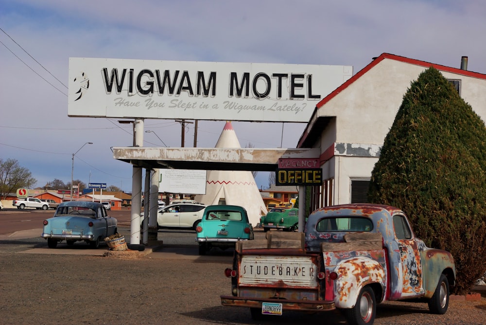 red and white vintage car parked beside white and green building during daytime