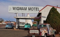 red and white vintage car parked beside white and green building during daytime