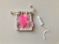 Flat lay of pastel pink and black menstrual underwear neatly arranged on a soft fabric background.