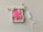 A bright pink menstrual cup is placed on top of a small, patterned drawstring pouch with a rope closure. Nearby, there is a white tampon with an extended string.