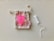 A bright pink menstrual cup is placed on top of a small, patterned drawstring pouch with a rope closure. Nearby, there is a white tampon with an extended string.