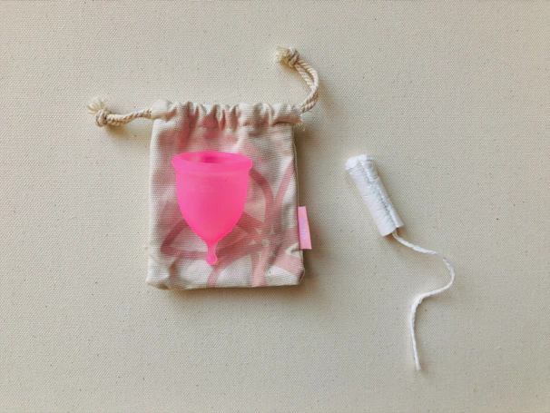 A hand holding a small, sleek no no knot pouch next to a used condom ready for disposal