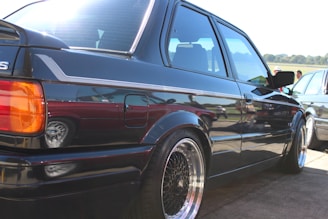 A shiny, freshly detailed car parked outdoors with sunlight reflecting off its polished surface.