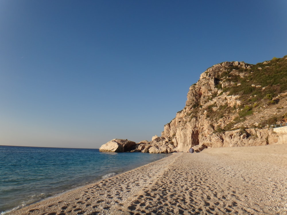 formação rochosa marrom na praia durante o dia