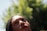 A close-up of a person looking upwards with a thoughtful expression. The background consists of lush greenery out of focus, suggestive of a natural setting.