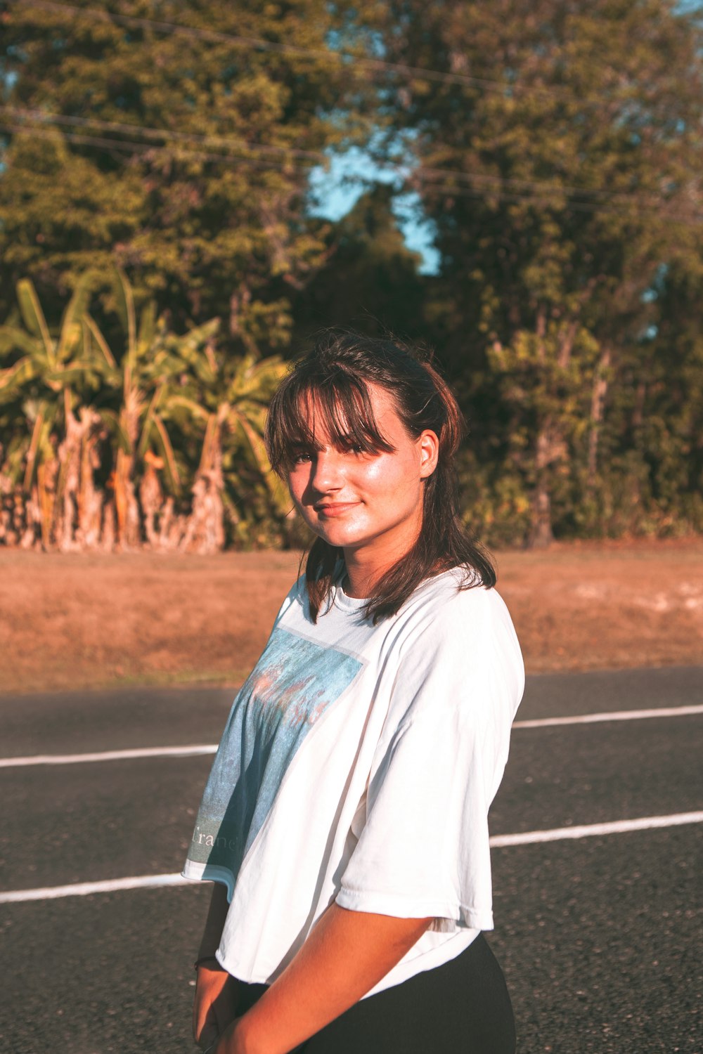 woman in white long sleeve shirt standing on road during daytime