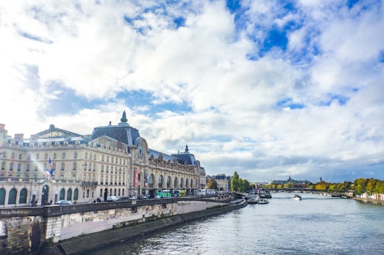 white and gray concrete building near body of water under white clouds and blue sky during in Tuileries Garden France