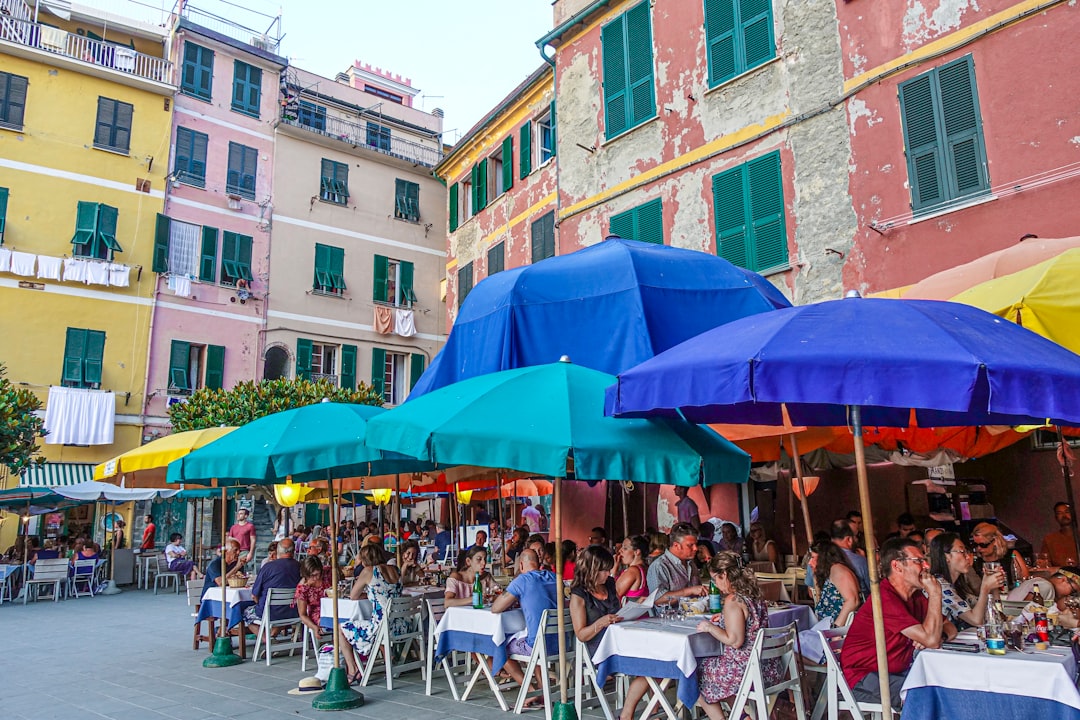 people sitting on white folding chairs under blue umbrella during daytime