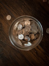 A close-up of coins and bills neatly arranged next to a savings jar with a sparfokus logo.