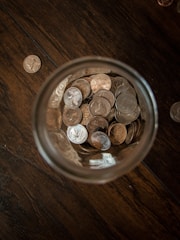 A close-up of coins being placed in a glass jar.