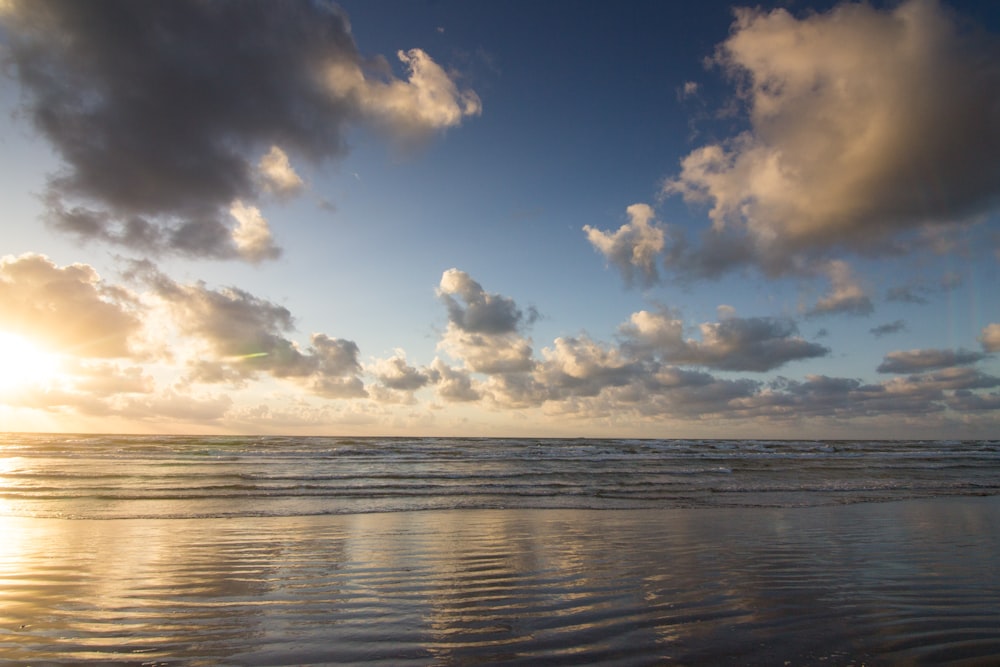 body of water under blue sky and white clouds during daytime