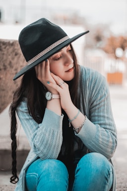 woman in blue knit sweater wearing brown fedora hat