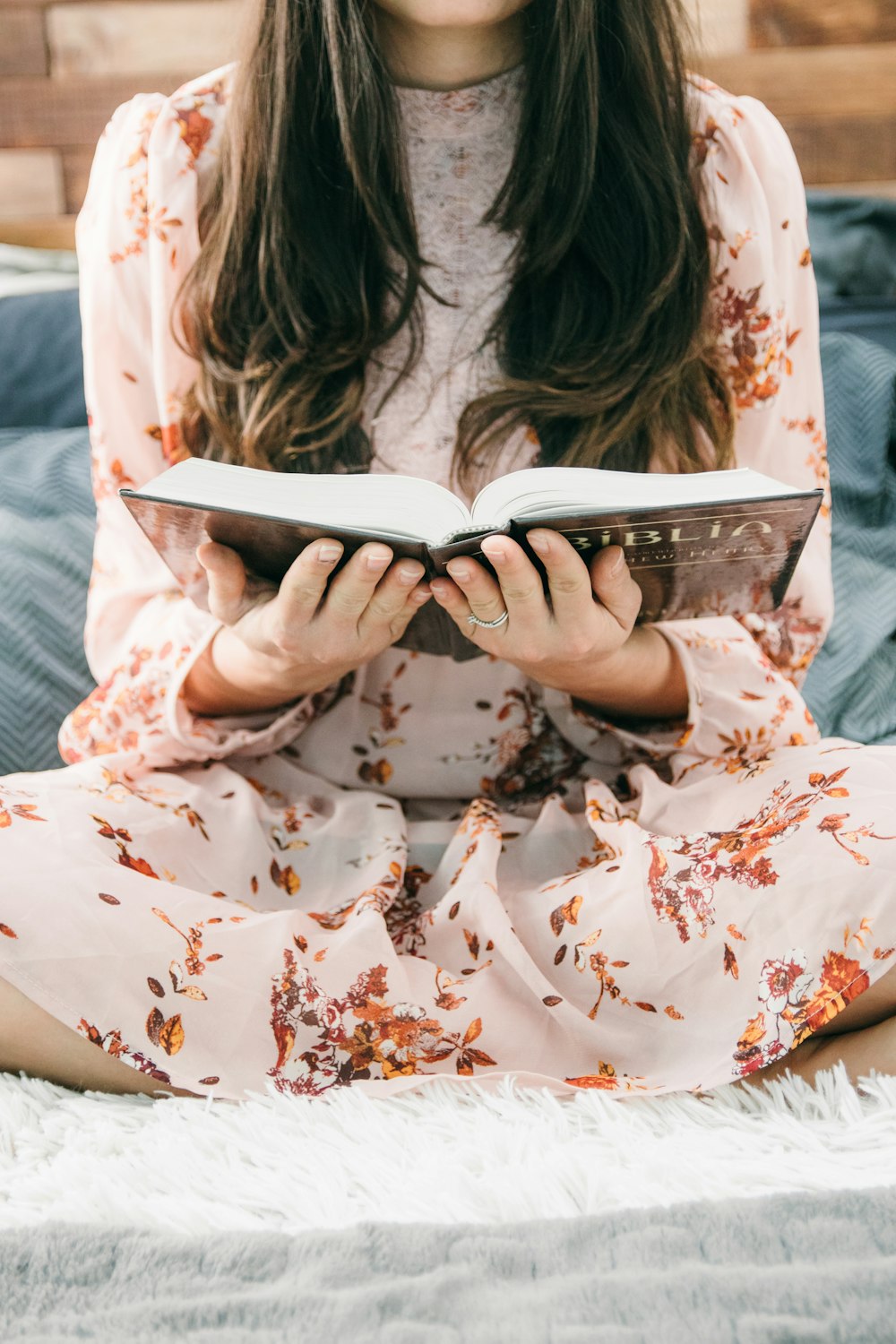 woman reading book on bed