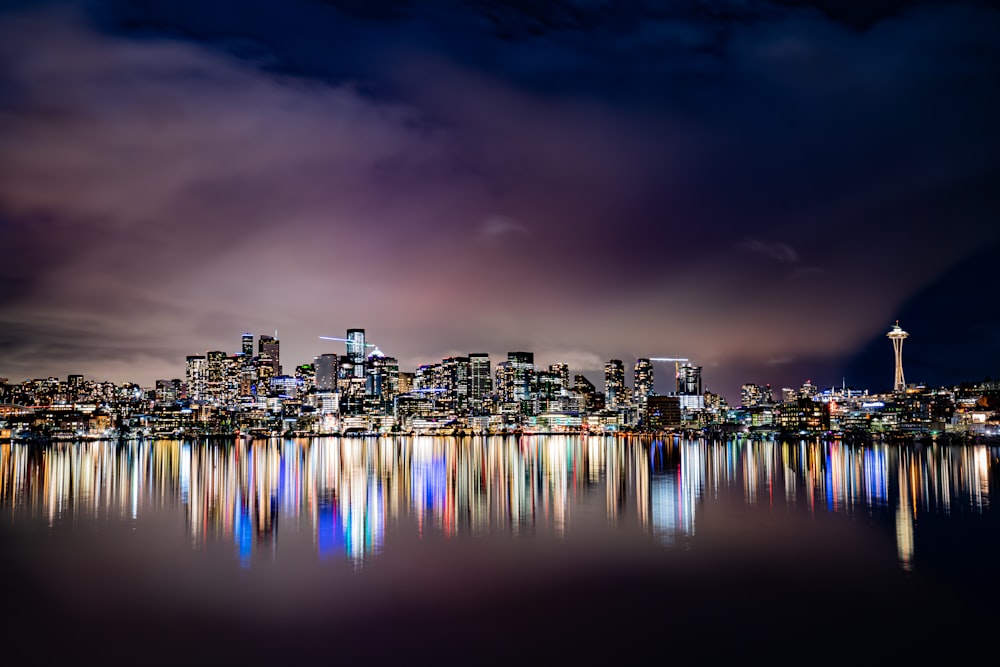 city skyline across body of water during night time