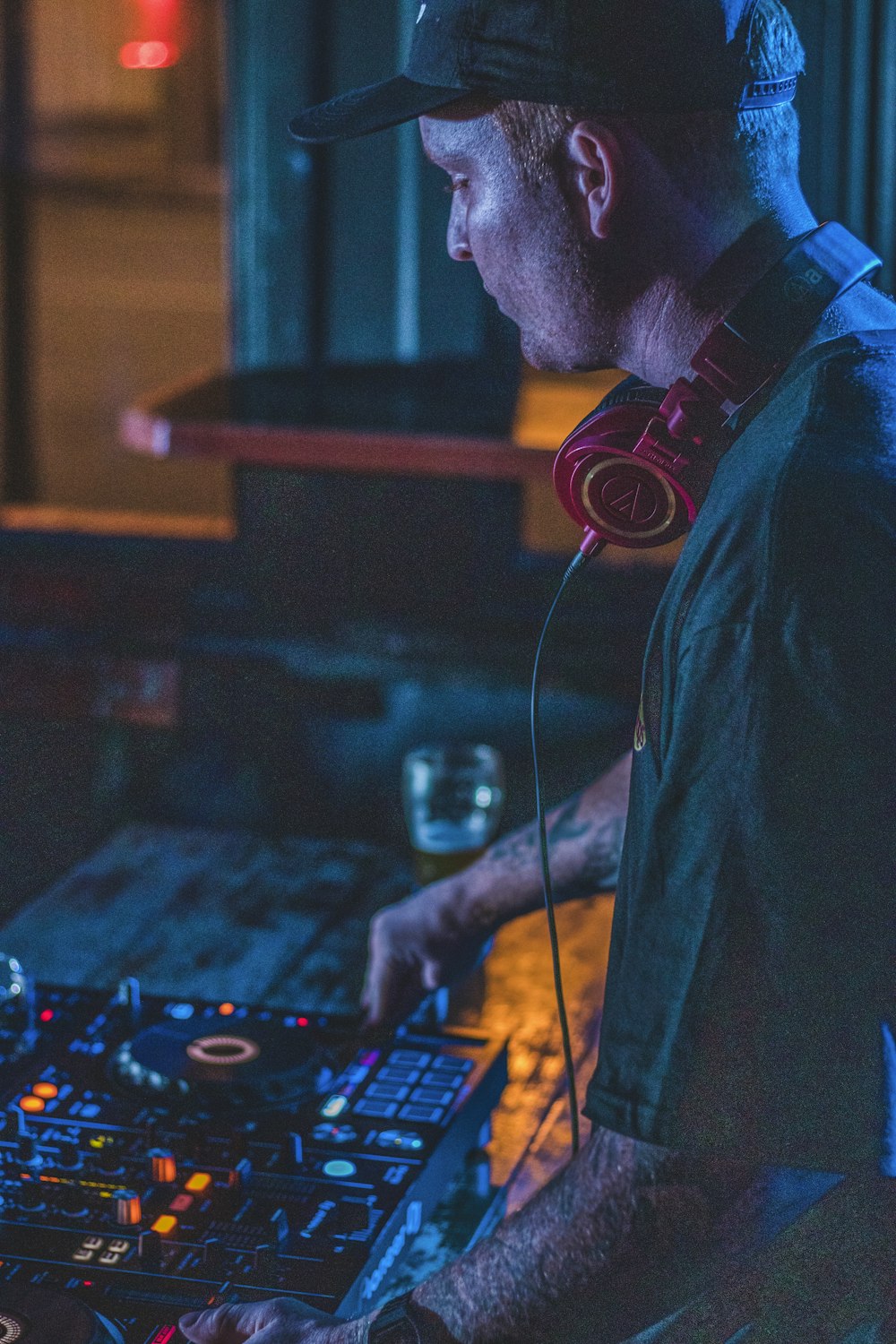 Mann im blauen Hemd mit schwarzen Kopfhörern spielt DJ-Controller