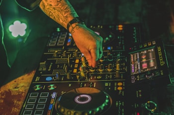 person playing dj mixer with green lights