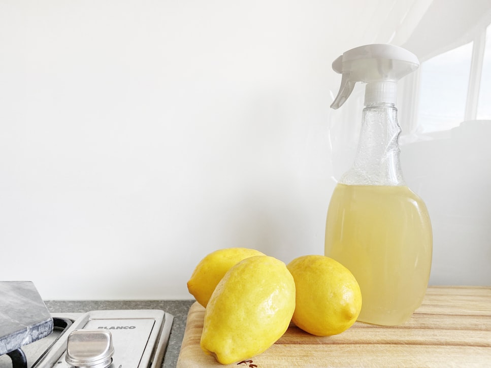 three lemons sitting next to an unlabeled spray bottle filled with what is presumed to be homemade cleaner