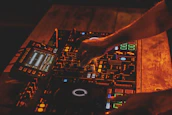 Dimly lit DJ hands adjusting knobs on classic analog gear, bathed in soft orange glow.