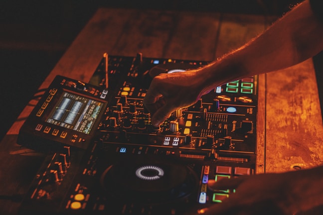 Hands adjusting the knobs on a vintage-style amplifier with warm lighting.