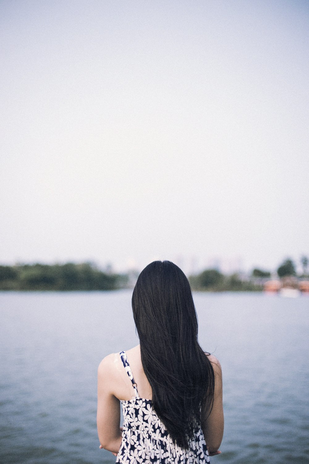 femme en haut de bikini blanc debout près du plan d’eau pendant la journée