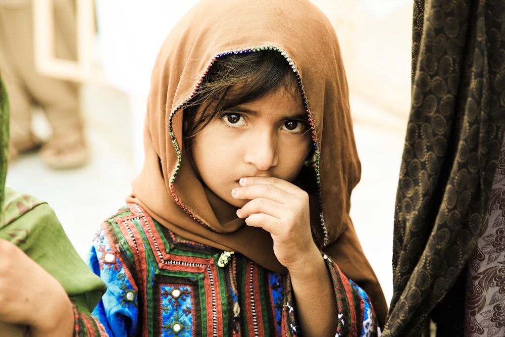 woman in brown hijab and blue and red floral dress