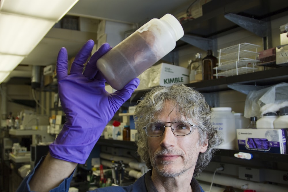 man in purple long sleeve shirt holding white plastic bottle