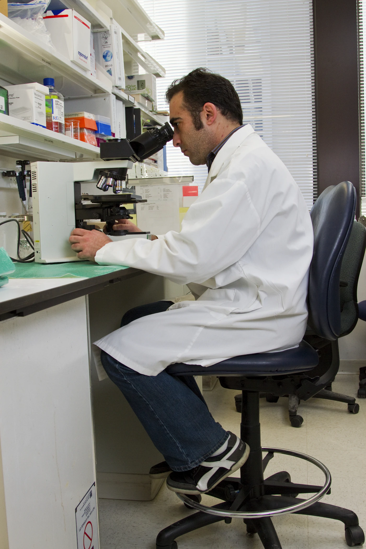 Illustrative stock photograph of a researcher using a microscope