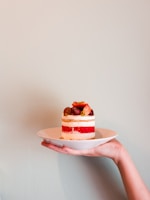 A beautifully crafted layered cake with fresh fruit topping on a white plate