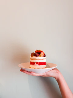 Freshly baked layered cake with vibrant fruit toppings on a ceramic plate.