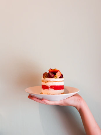 Freshly baked layered cake with vibrant fruit toppings on a ceramic plate.