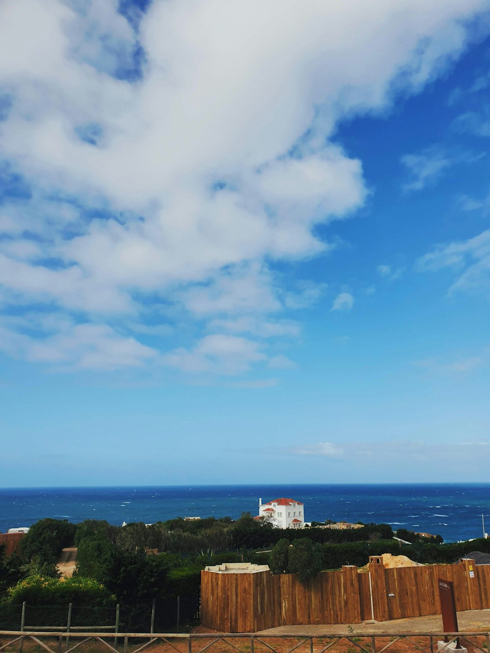 Edificio de hormigón blanco y marrón en la cima de una colina cerca del mar bajo el cielo azul durante el día