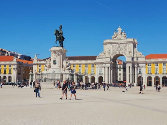 people walking on street near white concrete building during daytime in Praça do Comércio Portugal