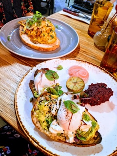 A close-up of a vibrant, colorful breakfast plate with avocado toast, poached eggs, and fresh herbs on a ceramic dish.
