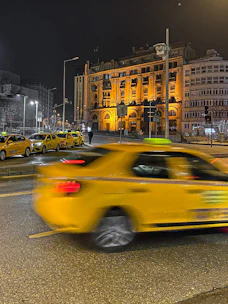 A professional taxi parked in front of a modern building in Valencia at sunset.