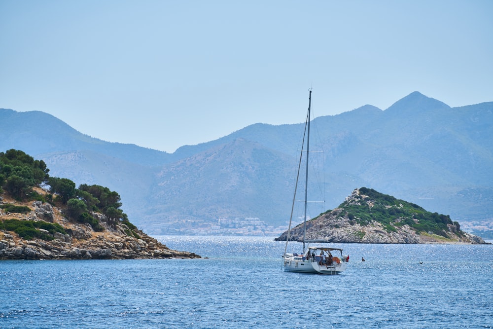 white boat on sea near mountain during daytime