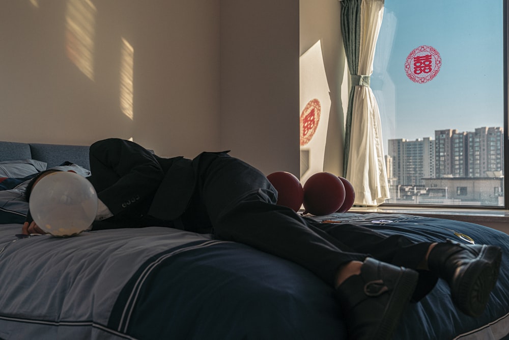 a man laying on top of a bed next to a window