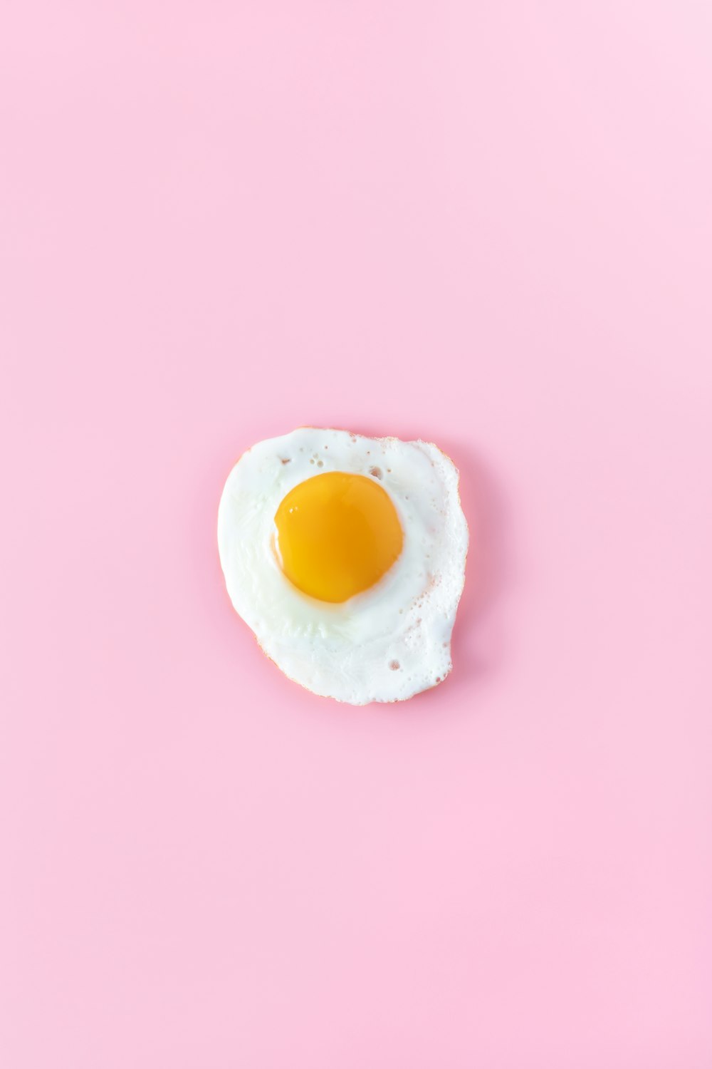 huevo con el lado soleado hacia arriba sobre una superficie rosada