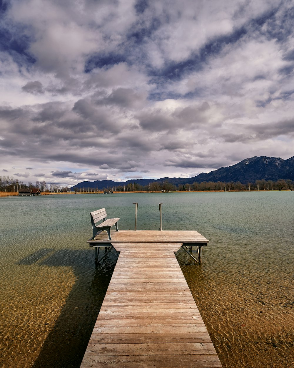 brown wooden dock on body of water under cloudy sky during daytime