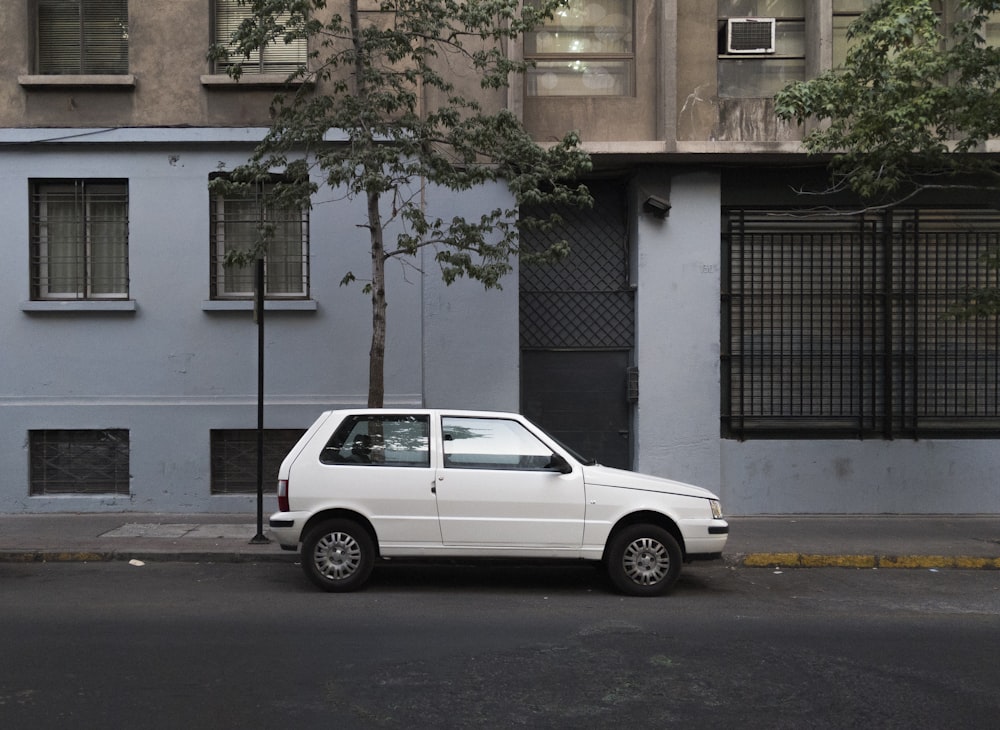 white suv parked beside green tree during daytime