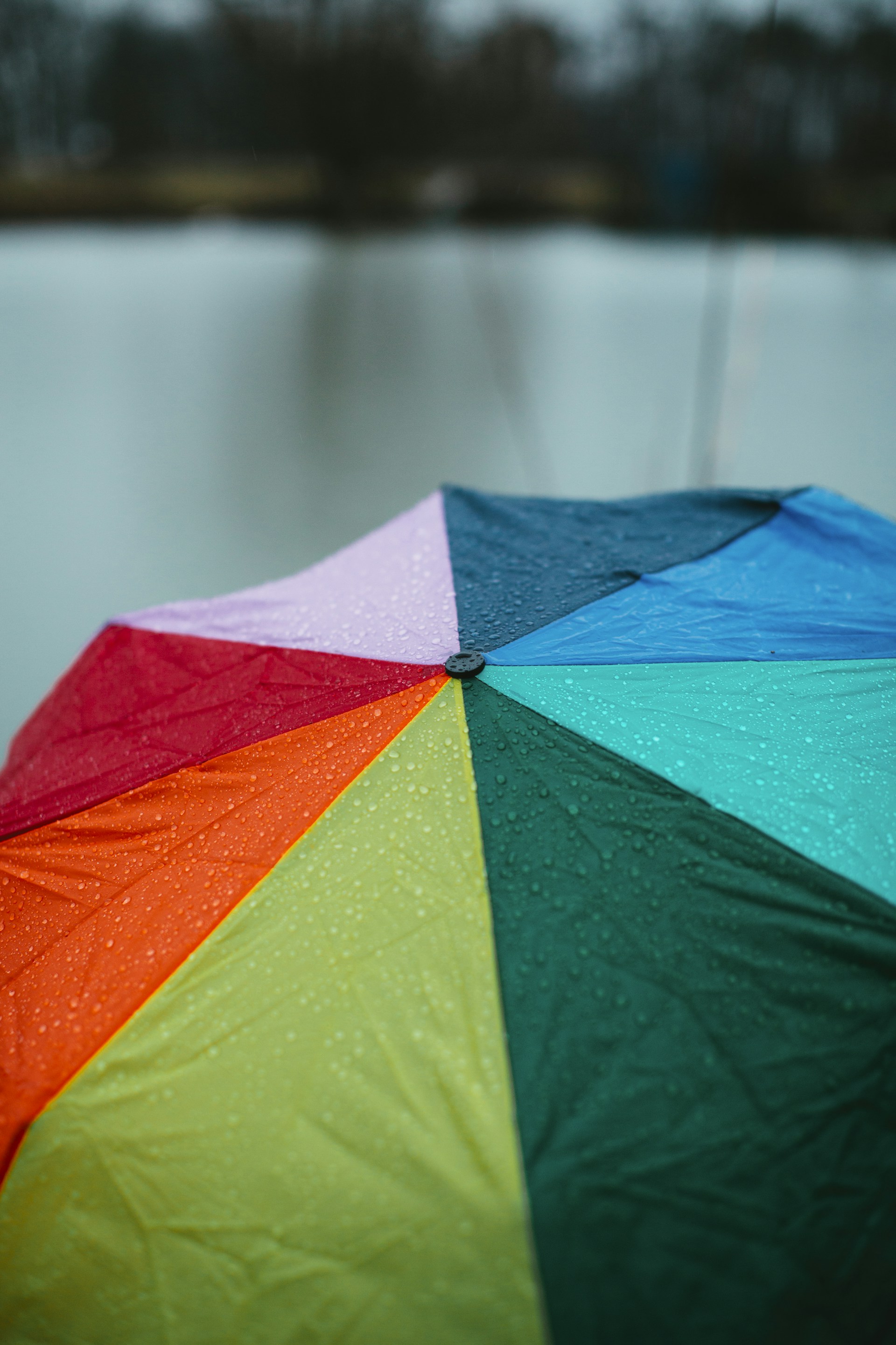 A vibrant umbrella open against a light rain backdrop, with colorful accessories arranged nearby.