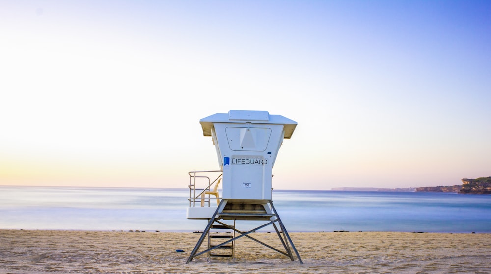 white lifeguard house on beach during daytime