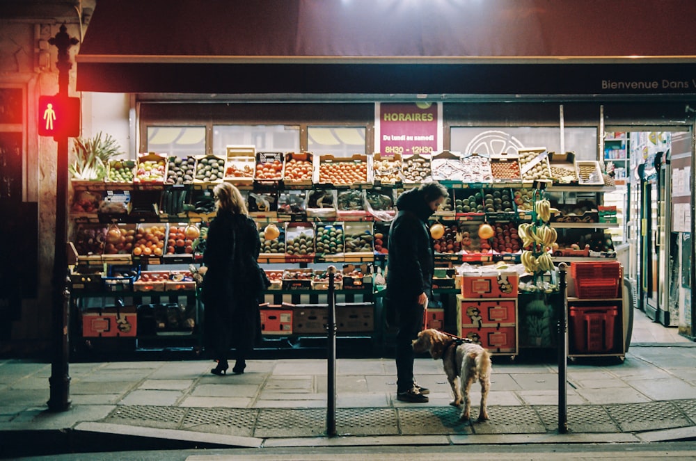 man in black jacket standing in front of food stall