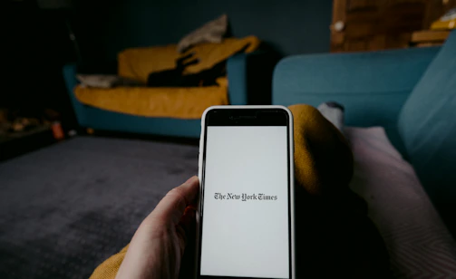 Close-up of a person reading a news article on a smartphone in a cozy home setting