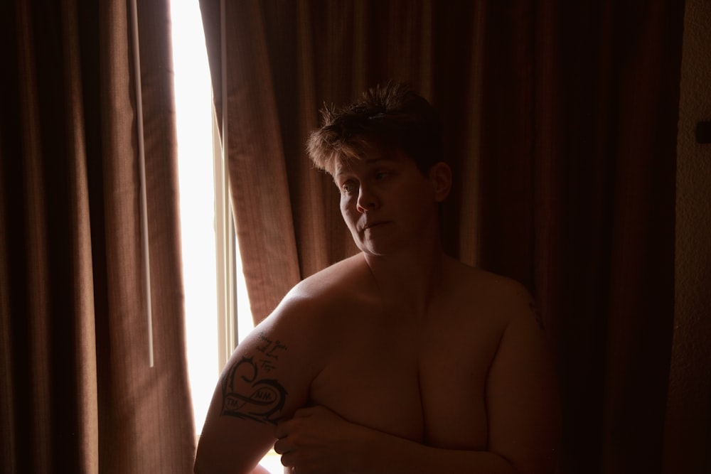 topless man sitting on chair near window