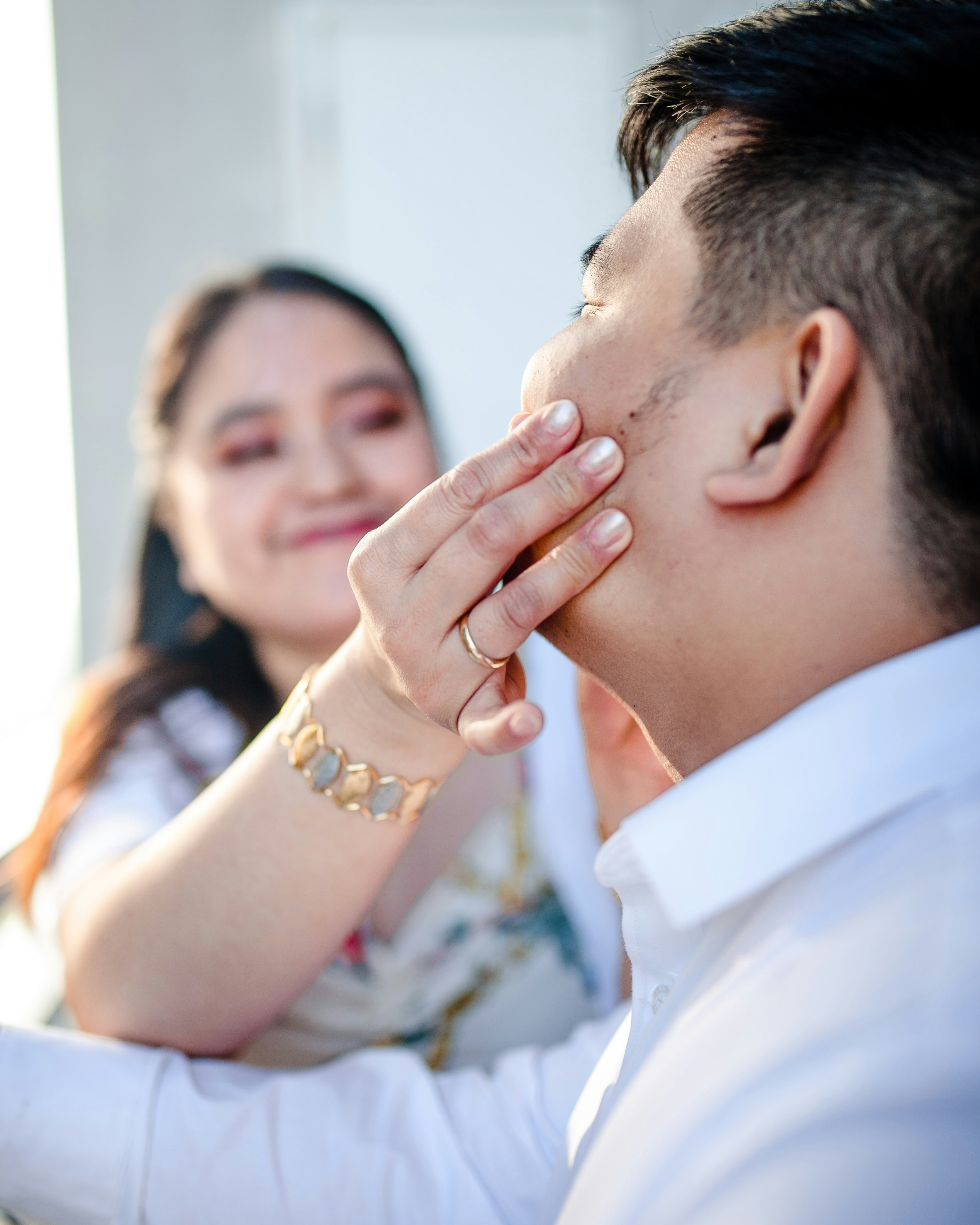 man in white dress shirt kissing womans cheek