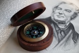 An open map spread across a wooden table with a compass.