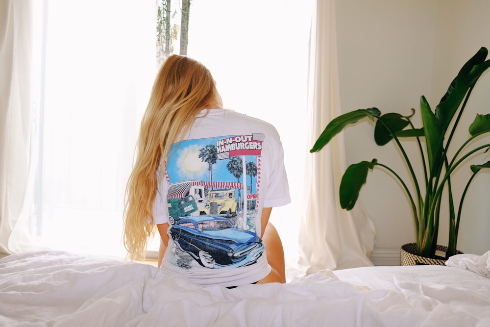 woman in white and blue crew neck t-shirt sitting on bed