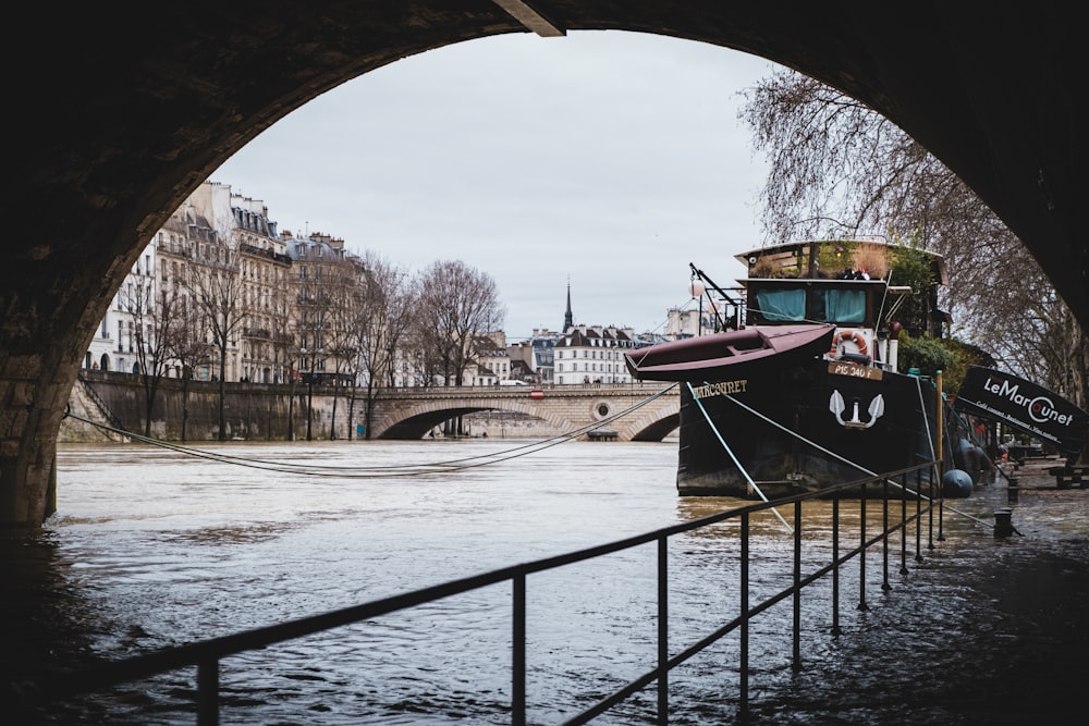 red and black boat on river under bridge during daytime