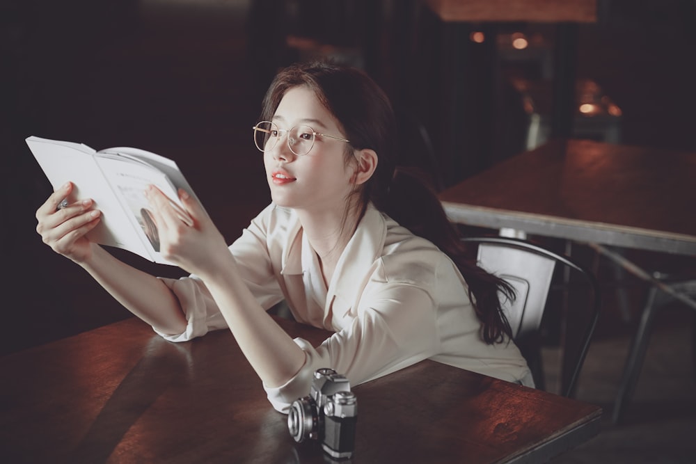 woman in white blazer reading book